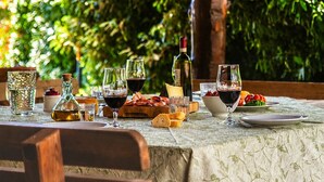 An outdoor dining area with a table set for a meal, surrounded by greenery. - An old Tuscan stone farmhouse with a pool and vineyard in the Val d'Orcia (Radicofani)