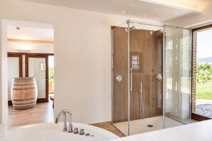 A modern bathroom with a glass-enclosed shower, a large wooden barrel, and a bathtub. - An old Tuscan stone farmhouse with a pool and vineyard in the Val d'Orcia (Radicofani)