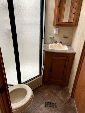 A compact bathroom with a toilet, sink, and window.