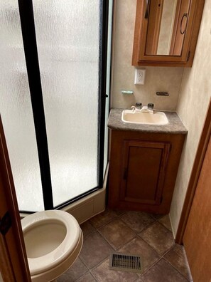 A compact bathroom with a toilet, sink, and window.