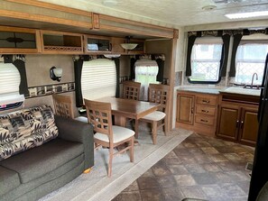 A compact RV interior with a dining area, kitchenette, and a sofa.