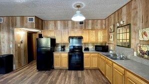 Une cuisine avec des meubles de rangement en bois, un réfrigérateur noir, une cuisinière et un four à micro-ondes.