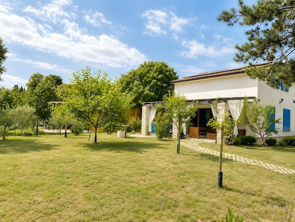Ein Haus mit Garten, einer Pergola und einer Steinmauer.