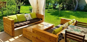 Eine hölzerne Sitzgruppe im Freien mit Tisch und Stühlen, umgeben von einem üppigen Grünpflanzen-Garten.