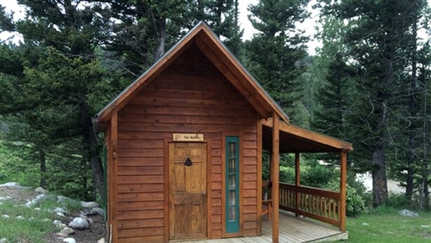 Una cabana de fusta amb una porta d'entrada, un porxo i un camí d'accés de grava.