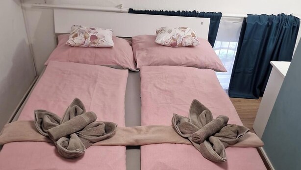 Un lit double avec une literie rose et des serviettes pliées posées sur le lit.