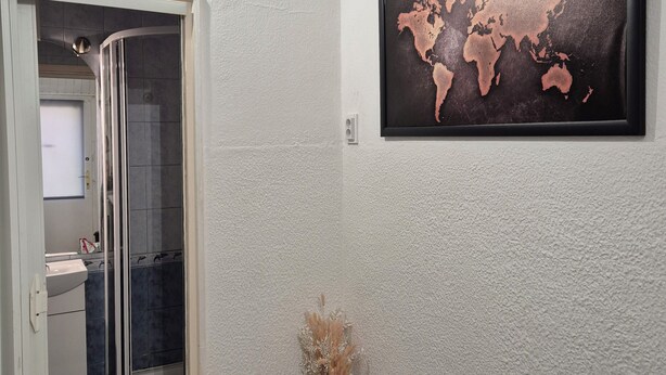 Ein Badezimmer mit Dusche, Waschbecken und einer an der Wand hängenden Weltkarte.
