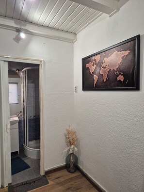 A bathroom with a shower, a sink, and a framed world map on the wall.
