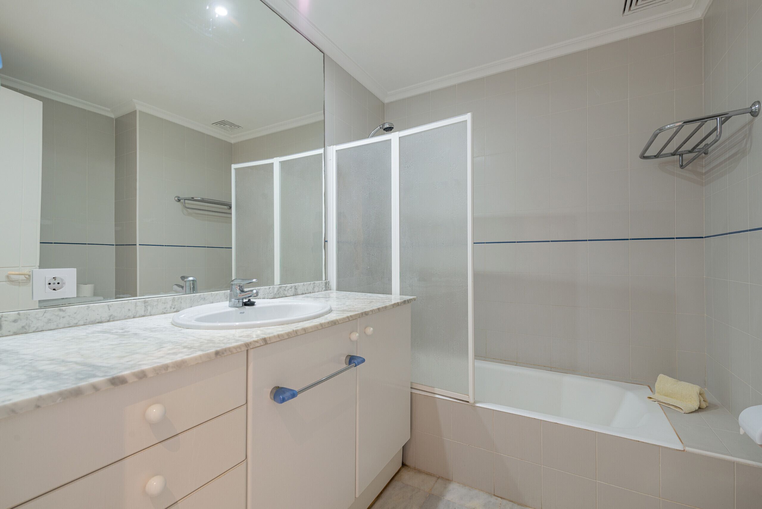 A bathroom with a marble sink, a large mirror, a glass shower enclosure, and a bathtub.