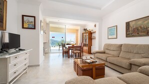 Ein Wohnzimmer mit Sofa, Couchtisch, Fernseher und einem Essbereich mit Stühlen und Tisch.