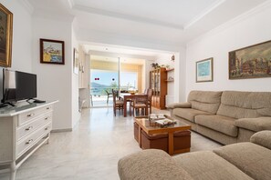Uma sala de estar com sofá, mesa de centro, TV e um espaço de jantar com cadeiras e mesa.