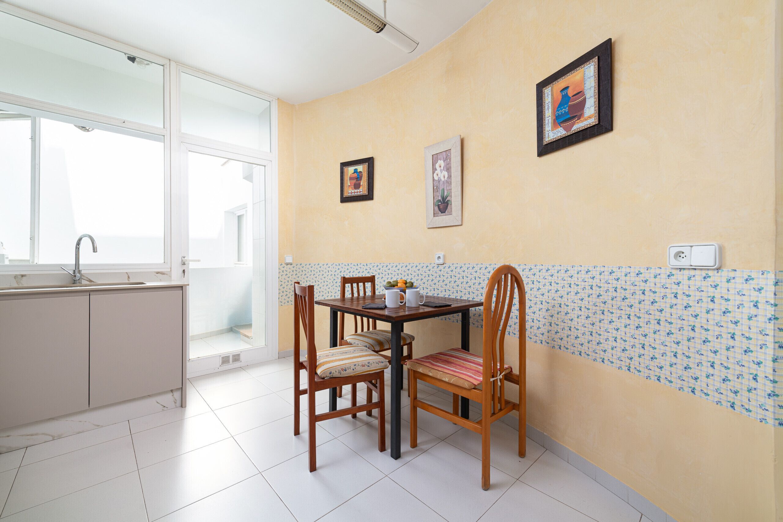 Une cuisine avec une table à manger, des chaises, une fenêtre et un évier.