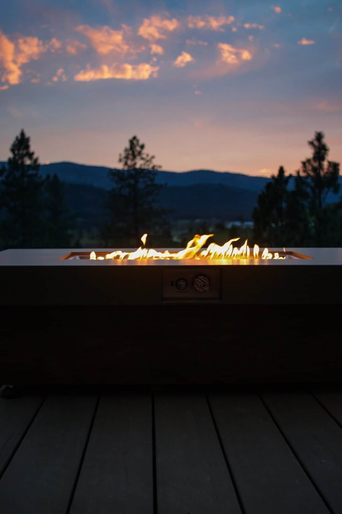 Ein Feuerstelle auf einer Terrasse mit Bergkulisse.