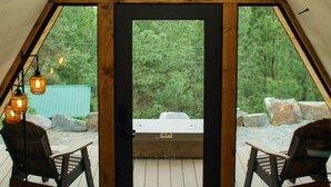 Una habitación de madera triangular con un ventanal grande, dos sillas y una mesa.