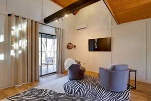 A modern living room with a zebra-patterned rug, two armchairs, a television, and a large window with curtains. - Secluded Studio Getaway with Outdoor Living and Trails Near Siloam Springs, Gentry, AR (Gentry)