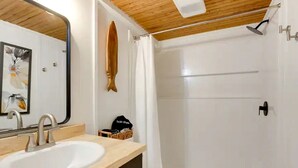 A bathroom with a wooden ceiling, a white sink, a shower with a glass door, and a towel rack. - Secluded Studio Getaway with Outdoor Living and Trails Near Siloam Springs, Gentry, AR (Gentry)