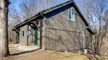 A rustic wooden building with a green roof, a door, and a window.