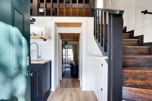 A modern interior with a kitchen, a staircase, and a view into another room.