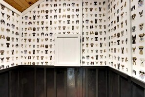 A room with a wall covered in dog portraits, a wooden ceiling, and a dark wooden bench.
