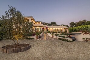 A modern building with a central staircase, arched windows, and a well-maintained garden.