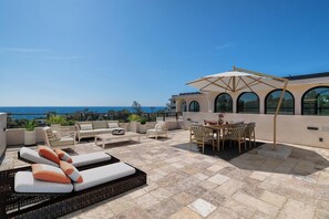 Une terrasse sur le toit, aménagée avec du mobilier d’extérieur, un espace repas et une vue sur la mer.