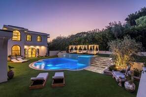 A modern house with a swimming pool, outdoor seating, and a well-maintained garden.