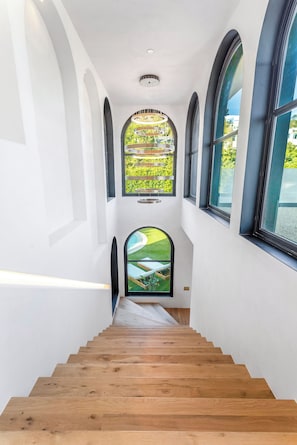 A modern interior with a wooden staircase leading to a balcony with a view.