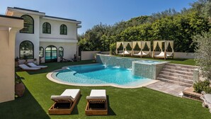 Una casa moderna amb piscina, mobiliari exterior i jardí ben cuidat.