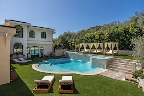 A modern house with a swimming pool, outdoor seating, and a well-maintained garden.
