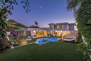Una casa grande con piscina, ventanas arqueadas y un césped bien cuidado.