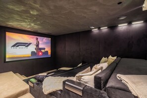 Une salle de cinéma privée dotée d’un grand écran, de sièges confortables et d’un intérieur aux couleurs sombres.