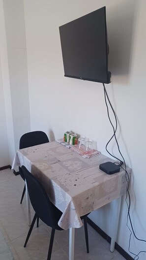 Ein Essbereich mit Tisch, Stühlen, einem an der Wand montierten Fernseher und einer Steckleiste auf dem Tisch.