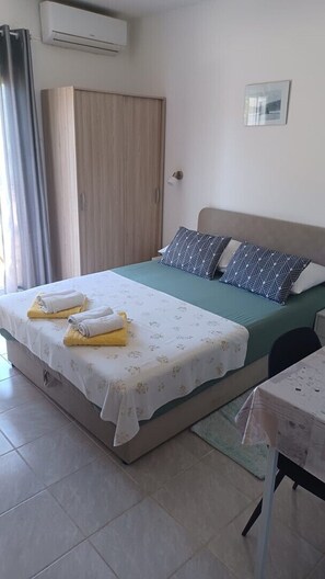 Ein Schlafzimmer mit Bett, Kissen, einem Tisch, einem Kleiderschrank und einer Klimaanlage.