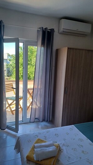 Ein Schlafzimmer mit Bett, Kleiderschrank, einer Schiebetür zu einem Außenbereich und einer Klimaanlage.