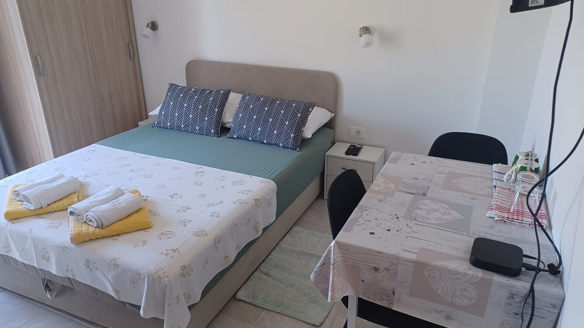 Een hotelkamer met een bed, nachtkastje, stoel en een bureau met een computer.