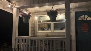 A porch with hanging flower pots, a blue door with a sign, and a white railing. - Farmhouse Retreat on 75 Acres with Fiber Wi-Fi, Near DeSoto (Mentone)