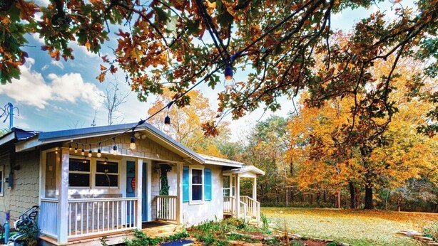 A house with a porch, a small garden, and trees with autumn leaves. - Farmhouse Retreat on 75 Acres with Fiber Wi-Fi, Near DeSoto (Mentone)