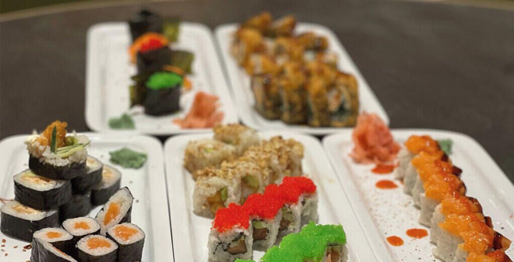 Une variété de plats de sushis présentés sur des assiettes rectangulaires.