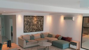 Una sala de estar moderna con un sofá modular, una mesa de centro y un cuadro abstracto de gran tamaño en la pared.