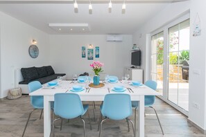 Ein Essbereich mit einem weißen Tisch, blauen Stühlen und einer Blumenvase.