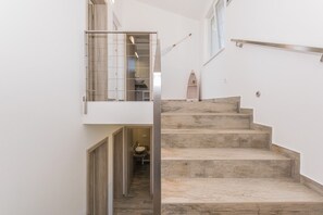 A staircase with a wooden finish, a glass railing, and a view into a bathroom with a sink. - Villa Sunset sea row (Medulin)