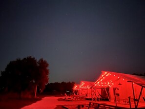A series of structures with red lighting, possibly a temporary event or exhibition, set against a night sky.