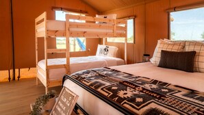 Habitación con literas, una colcha estampada, un cartel y una ventana.
