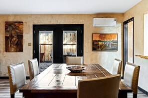 Comedor con una mesa de madera, seis sillas, dos puertas y obras de arte en las paredes.