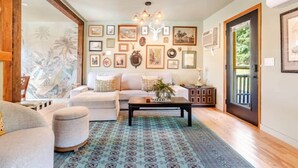 A living room with a sofa, ottoman, coffee table, and patterned rug. - The Catskill | Three Retreats One Creekside Escape (Jefferson Heights)