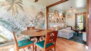 A dining area with a round table and chairs, a living room with a sofa and a coffee table, and a wall with framed pictures. - The Catskill | Three Retreats One Creekside Escape (Jefferson Heights)
