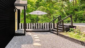 A covered outdoor area with a staircase, a table, and an umbrella. - The Catskill | Three Retreats One Creekside Escape (Jefferson Heights)