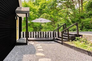 Ein überdachter Außenbereich mit Treppe, Tisch und Sonnenschirm.