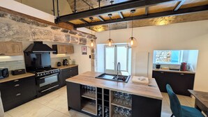 Een moderne keuken met een centraal eiland, een ingebouwde wijnopbergruimte en een accentmuur van steen.