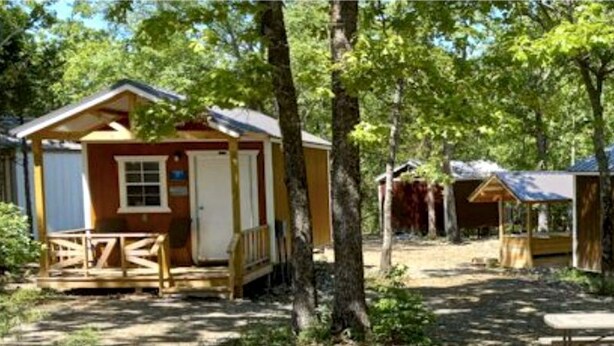 A row of wooden cabins with porches, surrounded by trees. - Peaceful Cabin Surrounded by Natural Beauty in Mena, Arkansas (Mena)